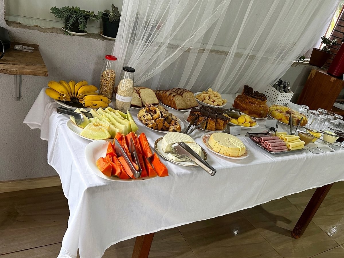 Mesa de café da manhã com frutas, pães, bolos e frios