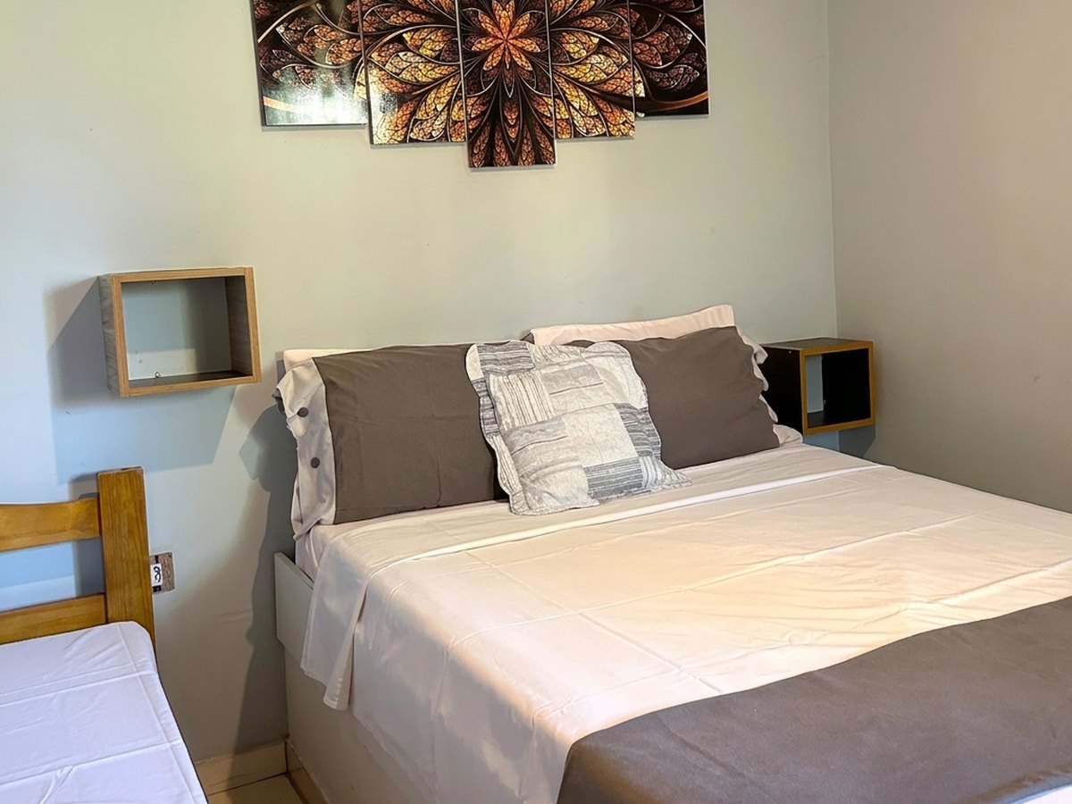 Quarto com cama de casal, cama de solteiro e quadro na parede